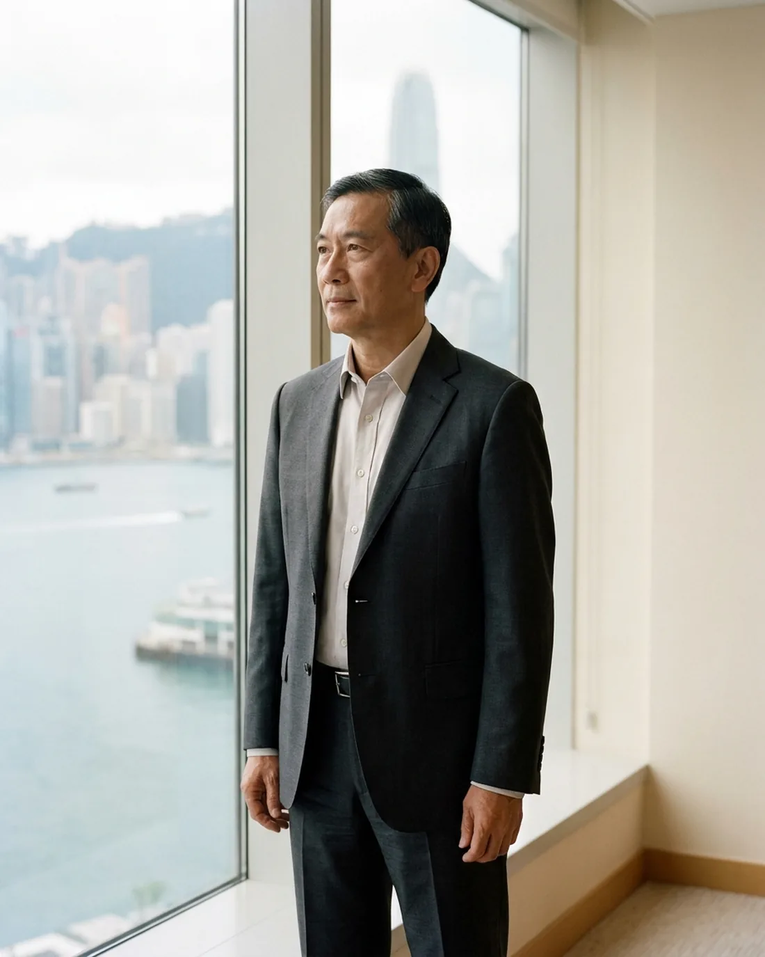 A senior executive standing composed by a window in a quiet office above the city